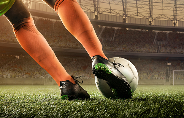 Pies de jugador de fútbol pateando pelota en una cancha