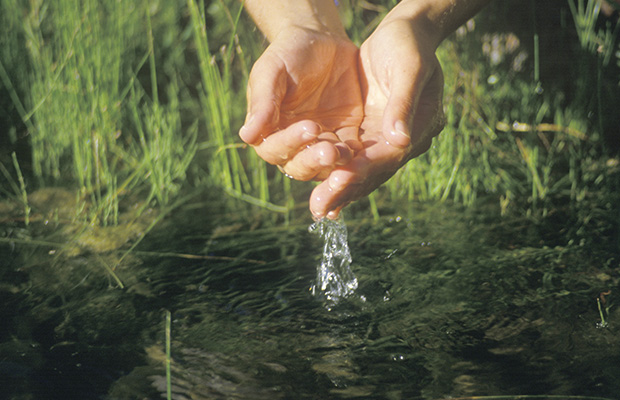 Mano tomando agua de un río para beber agua dulce