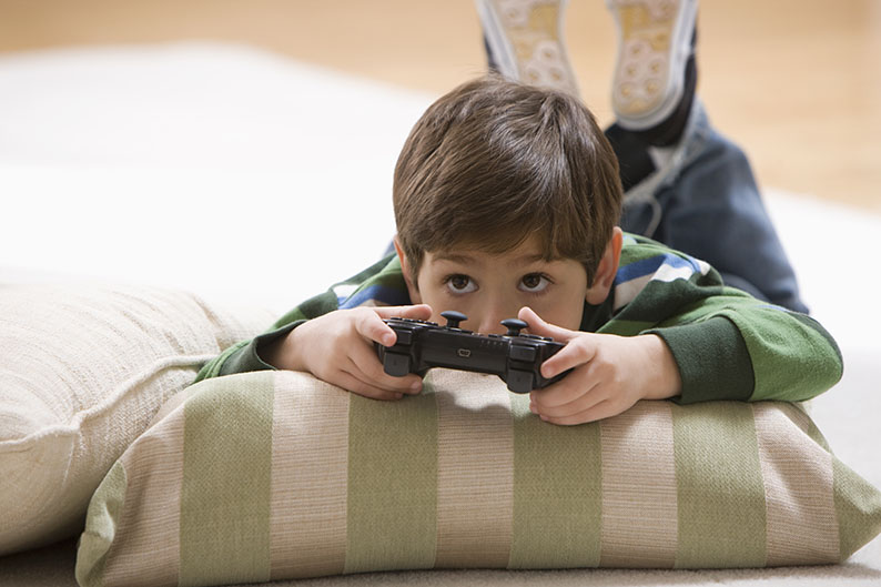 Niño. acostado, recargado, almohada, jugar, videojuegos, control