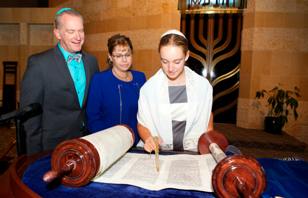 Niño leyendo la Torá en su Bar Mitzvá, con sus padres a su lado